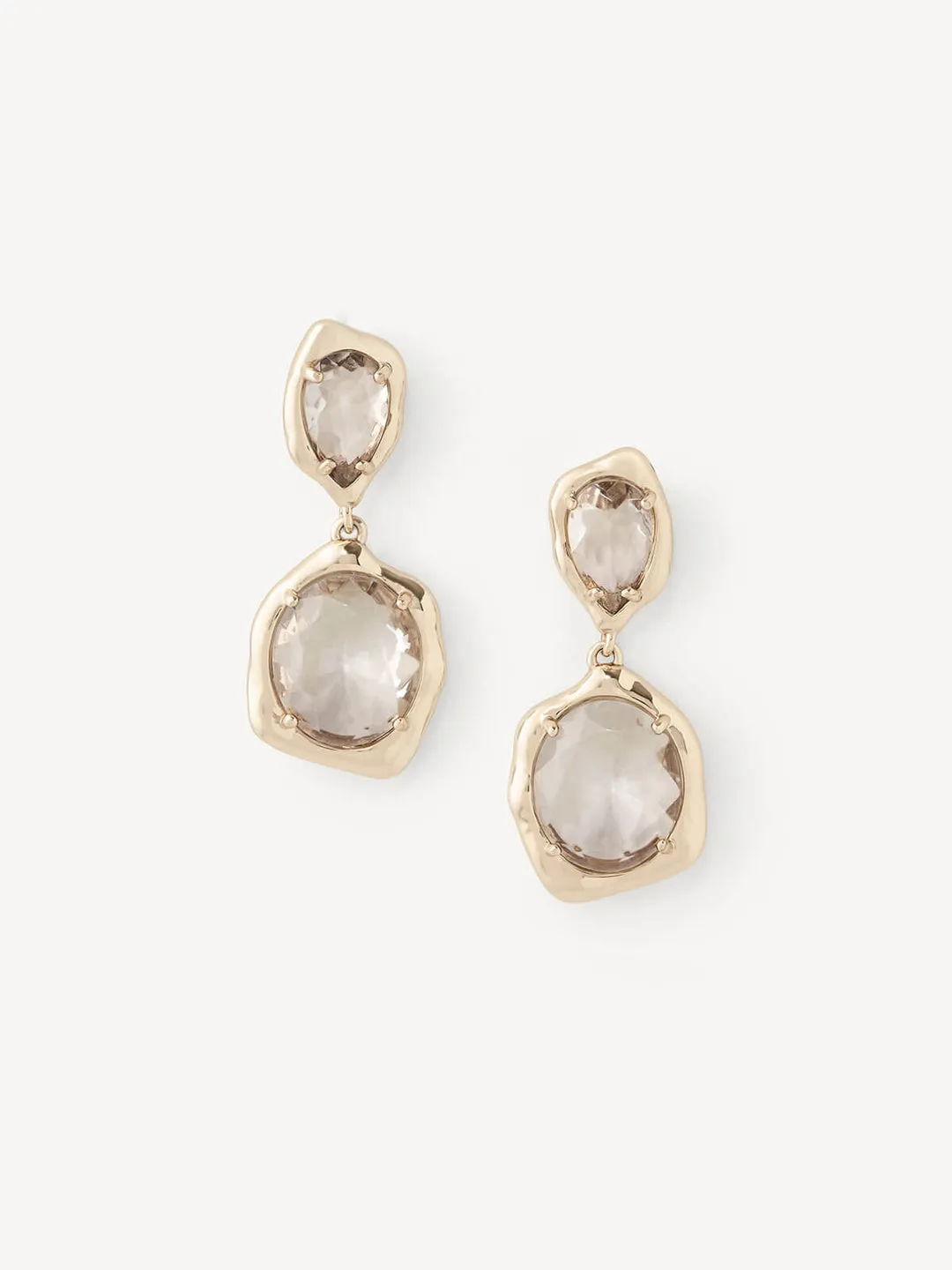 A pair of gold drop earrings with irregular organic-shaped clear gemstones, displayed on a clean off-white background.