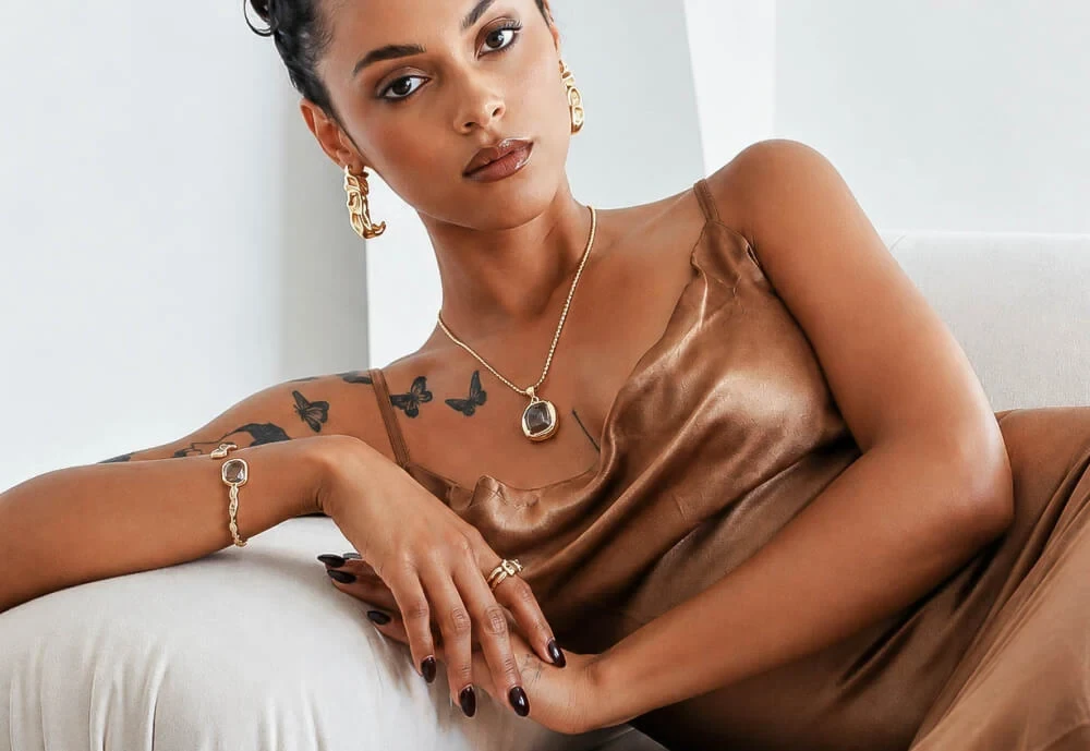 Model in a bronze satin slip dress wearing Organic Metals hoops, pendant necklace, cuff and rings