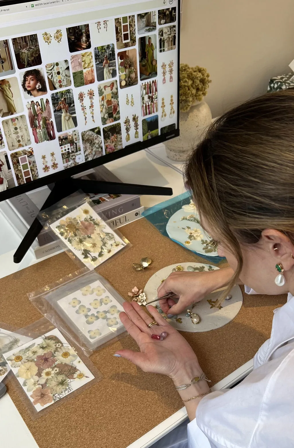 A designer at a desk arranging jewelry sketches and reference prints in the Vancouver studio
